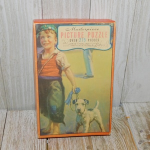 May include: Vintage box for a "Masterpiece Picture Puzzle" with over 275 pieces. The box features a colorful illustration of a young boy walking a dog with a blue ribbon. The boy is wearing a red and white striped shirt, blue pants, and a blue hat. The dog is a white terrier with brown spots.
