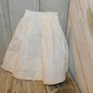 May include: A white cotton skirt with a lace trim. The skirt is gathered at the waist and has a simple, classic design.
