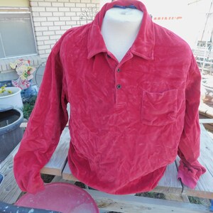 May include: A long-sleeved red velour shirt with a button-up collar and a single pocket on the left chest.