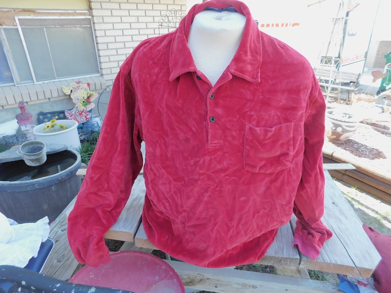 May include: A long-sleeved red velour shirt with a button-up collar and a single pocket on the left chest.