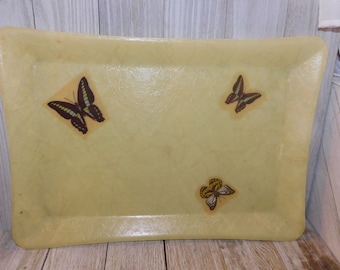 May include: A rectangular, pale yellow serving tray with rounded corners. The tray is decorated with three butterfly decals in shades of brown, green, and yellow. The tray has a slightly textured surface.
