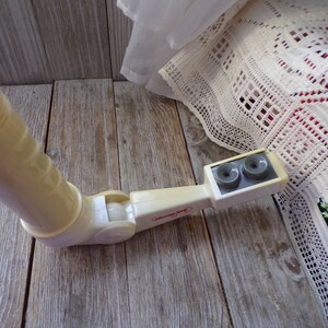 May include: A white plastic toy periscope with two gray viewing lenses. The periscope has a swivel joint and a handle.