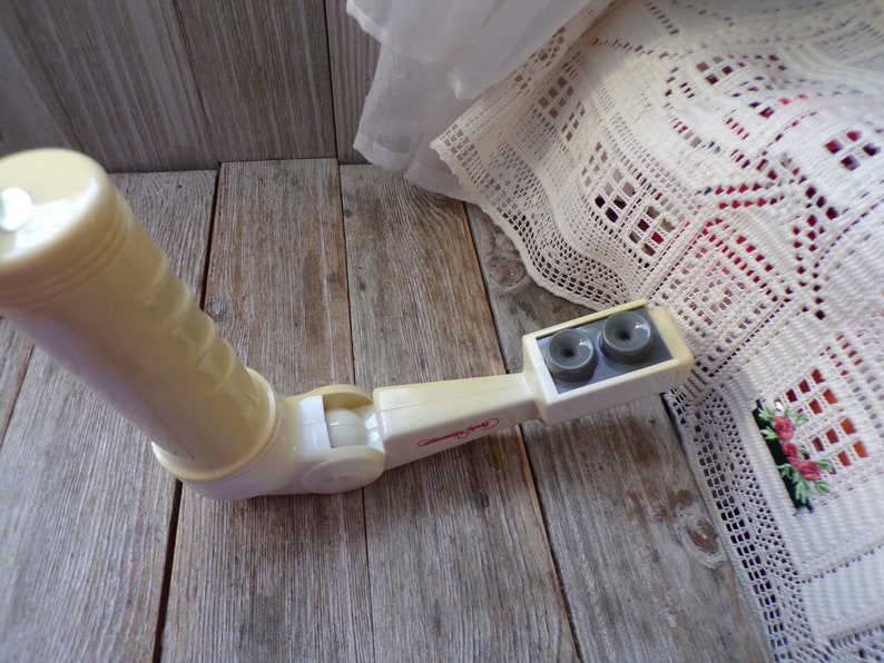 May include: A white plastic toy periscope with two gray viewing lenses. The periscope has a swivel joint and a handle.