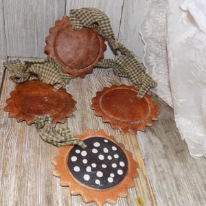May include: A rustic, brown, and green garland with four round, scalloped, wooden ornaments. One ornament has a black and white polka dot design.
