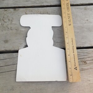Peut inclure: D&eacute;coupe en carton blanc d'une personne portant un chapeau. La d&eacute;coupe mesure environ 18 cm de haut.