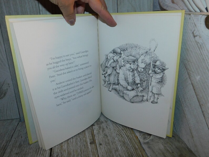 May include: A black and white illustration of a group of children standing around a basket. The children are looking into the basket. The text in the image reads, "I'm happy to see you," said Grandpa as he hugged the boys, "but what brought you all the way up here?" Grandma baked a cake, answered Peter. "And she asked us to bring a piece to you."