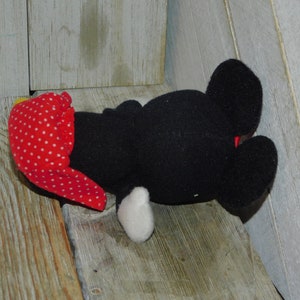 May include: Black and white plush toy with red polka dot fabric on its head. The toy is lying on its back with its legs in the air.