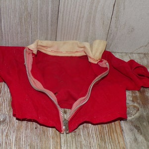 May include: Red zippered jacket with a white collar. The jacket is made of a soft, fuzzy fabric.