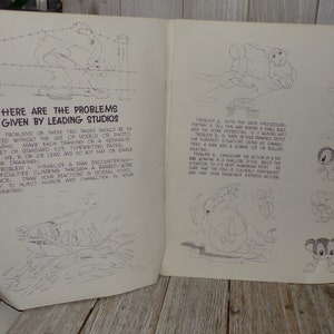 May include: Open book with cartoon sketches and text. The text reads "Here are the problems given by leading studios." The sketches depict various cartoon scenarios, including a man climbing a barbed-wire fence and a man rowing a boat.