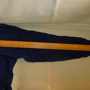 May include: A navy blue long-sleeved sweatshirt with a wooden ruler measuring 61 cm across the sleeve.