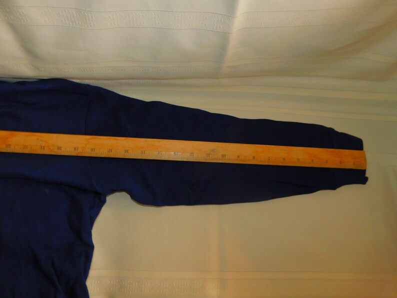 May include: A navy blue long-sleeved sweatshirt with a wooden ruler measuring 61 cm across the sleeve.