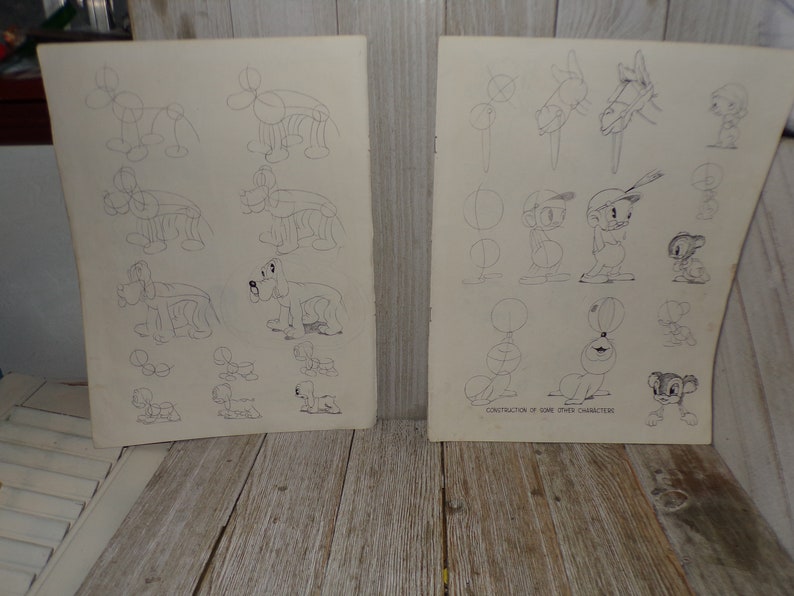 May include: Two vintage sheets of paper with pencil sketches of cartoon characters. One sheet features dog drawings, the other has various cartoon figures. The text "CONSTRUCTION OF SOME OTHER CHARACTERS" is visible.