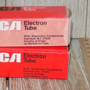 May include: Two red RCA Electron Tube boxes are stacked, displaying white text. The boxes have the RCA logo and the words "Electron Tube." Text on the boxes includes the manufacturer's location in Harrison, NJ.