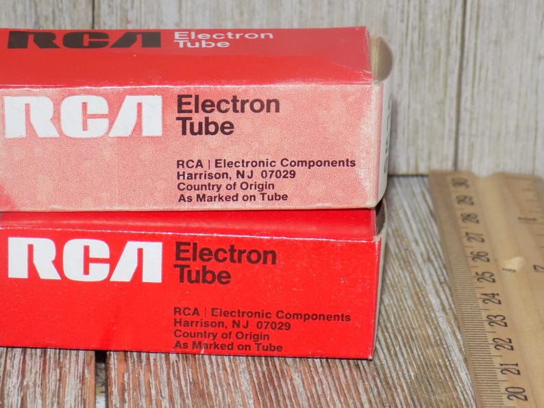 May include: Two red RCA Electron Tube boxes are stacked, displaying white text. The boxes have the RCA logo and the words "Electron Tube." Text on the boxes includes the manufacturer's location in Harrison, NJ.