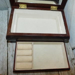 May include: A dark wood jewelry box with a hinged lid and a mirror inside. The box has a removable tray with ring rolls.