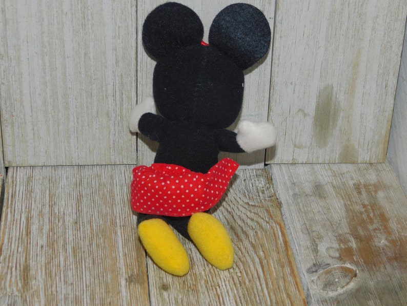 May include: A black and red plush toy of Minnie Mouse. She is wearing a red skirt with white polka dots and has yellow shoes.