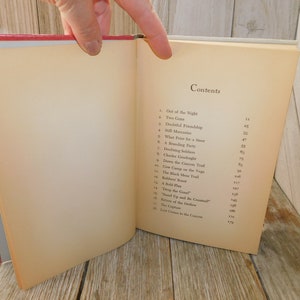 May include: A book with a cream-colored cover and a black title "Contents" on the front. The book has a table of contents listing chapter titles and page numbers. The book is open to the table of contents page.