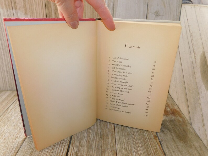 May include: A book with a cream-colored cover and a black title "Contents" on the front. The book has a table of contents listing chapter titles and page numbers. The book is open to the table of contents page.