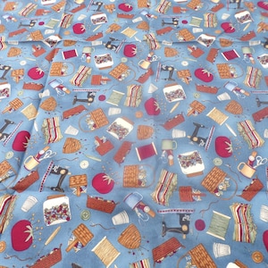 May include: Blue fabric with a repeating pattern of sewing-themed images, including sewing machines, spools of thread, buttons, jars of buttons, baskets, and tomatoes.