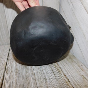 May include: Black ceramic skull planter with a smooth, matte finish. The planter is round and has a slightly pointed top.