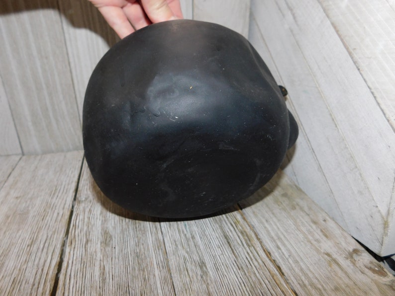 May include: Black ceramic skull planter with a smooth, matte finish. The planter is round and has a slightly pointed top.