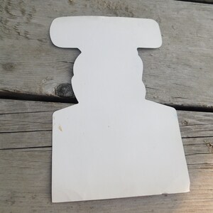 Peut inclure: D&eacute;coupe en carton blanc d'une personne portant un chapeau. La d&eacute;coupe est vide et a un design simple.