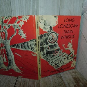 May include: A vintage children's book cover with a red background. The cover features a black and white illustration of a train engine and a child running away from it. The title of the book is "Long Lonesome Train Whistle" by Virginia H. Ormsby.