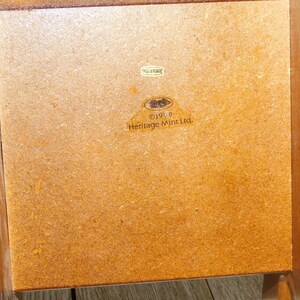 Puede incluir: Una caja de madera marr&oacute;n con una etiqueta que dice "&copy;1990 Heritage Mint Ltd."