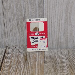 Pode incluir: Uma embalagem de cart&atilde;o vermelho e branco de agulhas Milwards, tamanho 97, com o pre&ccedil;o de 15 c&ecirc;ntimos. A embalagem diz "Nickel Plated" e "Large Eye Needles".