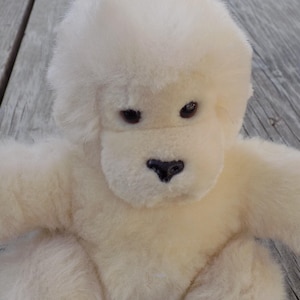 May include: A plush, off-white gorilla toy with a soft, furry texture. The toy has dark brown eyes and a black nose. The gorilla is sitting with its arms outstretched, inviting a hug. A classic children's toy.