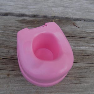 May include: A pink plastic potty training seat for toddlers.