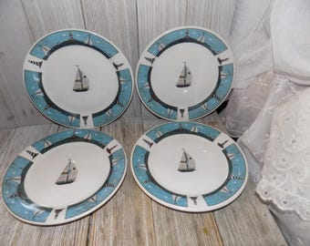 Può includere: Set di quattro piatti da insalata in ceramica bianca con un design nautico blu e bianco con barche a vela. I piatti hanno un centro bianco con un bordo blu e un motivo blu e bianco di barche a vela e fari.