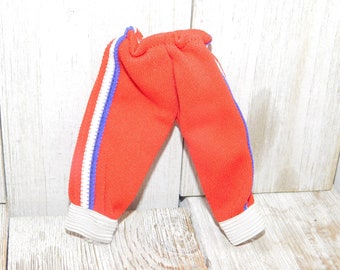May include: Red sweatpants with white and purple stripes down the sides. The sweatpants have a white elastic waistband and white cuffs.