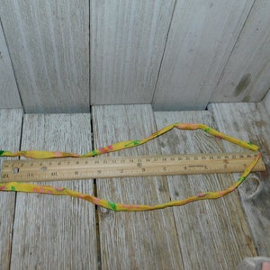 May include: A yellow fabric ribbon with pink and green floral print. The ribbon is approximately 27 inches long and is measured with a ruler.