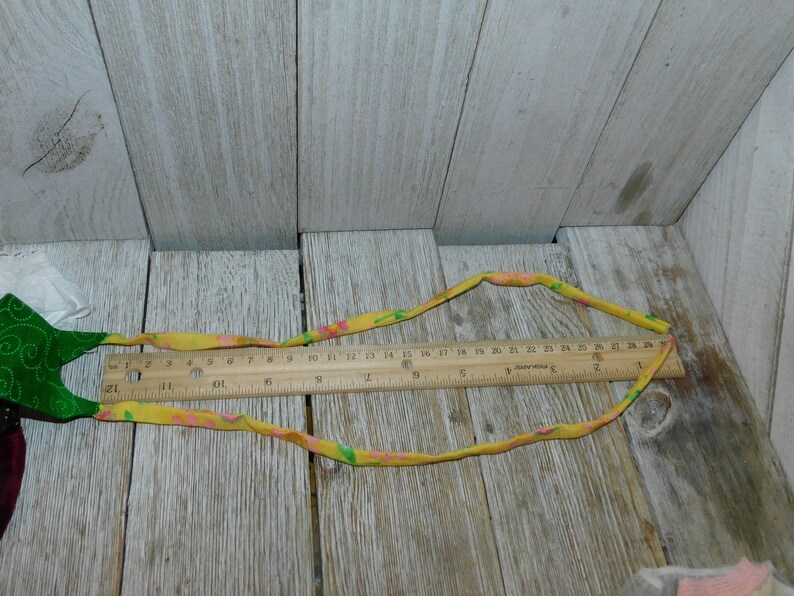 May include: A yellow fabric ribbon with pink and green floral print. The ribbon is approximately 27 inches long and is measured with a ruler.