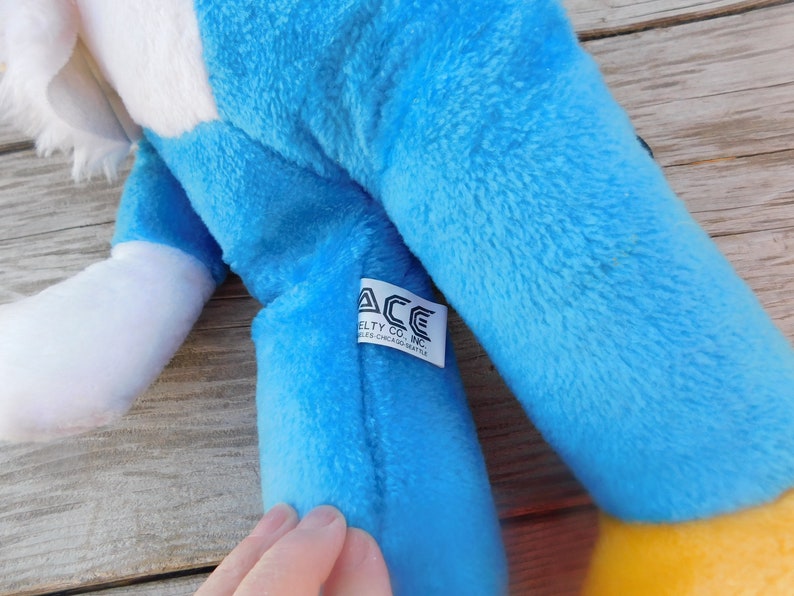 May include: Blue and white plush toy eagle with a yellow beak and feet. The toy has a tag that reads "ACE Novelty Co., Inc. Niles, Chicago, Seattle."
