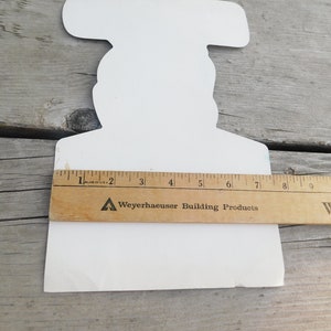 Peut inclure: D&eacute;coupe en carton blanc d'une personne tenant un marteau. La d&eacute;coupe mesure environ 18 cm de haut. Une r&egrave;gle est plac&eacute;e sous la d&eacute;coupe pour r&eacute;f&eacute;rence de taille. La r&egrave;gle est &eacute;tiquet&eacute;e "Weyerhaeuser Building Products".