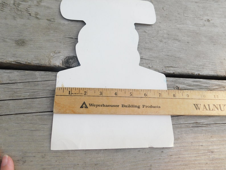 Peut inclure: D&eacute;coupe en carton blanc d'une personne tenant un marteau. La d&eacute;coupe mesure environ 18 cm de haut. Une r&egrave;gle est plac&eacute;e sous la d&eacute;coupe pour r&eacute;f&eacute;rence de taille. La r&egrave;gle est &eacute;tiquet&eacute;e "Weyerhaeuser Building Products".