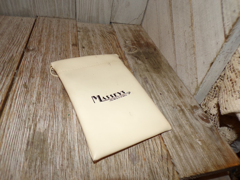 Puede incluir: Una bolsa blanca con el texto "Massey's Jewellers" impreso en negro.