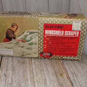May include: Vintage electric windshield scraper box. The box features a woman scraping ice off a car window. The red label reads "Electric Windshield Scraper" with product features. The box is beige with a diamond pattern.