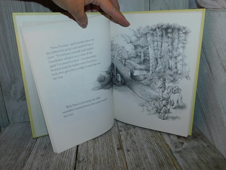 May include: A black and white illustration of a group of people and a horse walking down a path through a forest. The text "Now, Peaches," "said Grandmother as she rubbed the pony's ear and fed her a carrot." "You behave yourself and maybe Grandfather will give you a bite of the apple I've packed in here." Grandmother finished tying the basket onto Peaches's back, then gave her a nudge to start her on her way." and "With Peter in the lead, the little expedition moved down the road toward the river." is visible in the image.