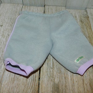 May include: Gray sweatpants with purple trim and a green label. The sweatpants have a drawstring waist and a relaxed fit.