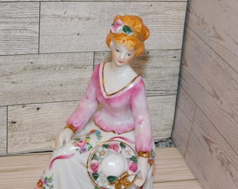 Dama victoriana sentada en un taburete, sosteniendo un sombrero, figura de cerámica, flores rosas, recuerdos de tareas de la casa de campo, regalo, utilería, tesoros de días pasados *y