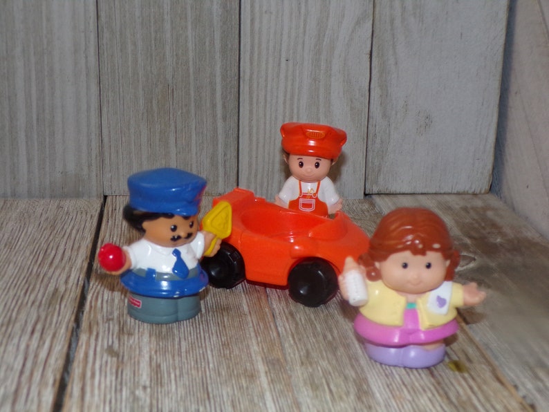 May include: A set of three Little People figurines, including a police officer holding a red ball, a construction worker in an orange jumpsuit sitting in a red car, and a girl with brown hair holding a bottle.