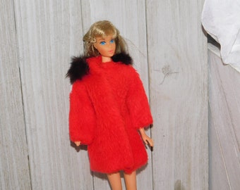 May include: A vintage Barbie doll wearing a red fuzzy coat with a black fur collar. The doll has blonde hair and blue eyes.