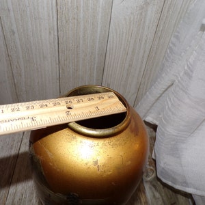 May include: A gold-colored ceramic vase with a wide mouth and a rounded body. The vase is approximately 9 inches tall.