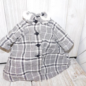 May include: A black and white plaid coat with a white faux fur collar and black buttons.