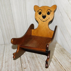 Puede incluir: Una silla mecedora de madera con forma de oso con la cara pintada. La silla es marr&oacute;n y tiene un dise&ntilde;o sencillo.