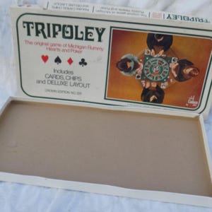 May include: A Tripoley board game box with a white lid featuring the text Tripoley, The original game of Michigan Rummy, Hearts and Poker, and Includes Cards, Chips and Deluxe Layout. The lid shows a graphic of four people playing a card game.