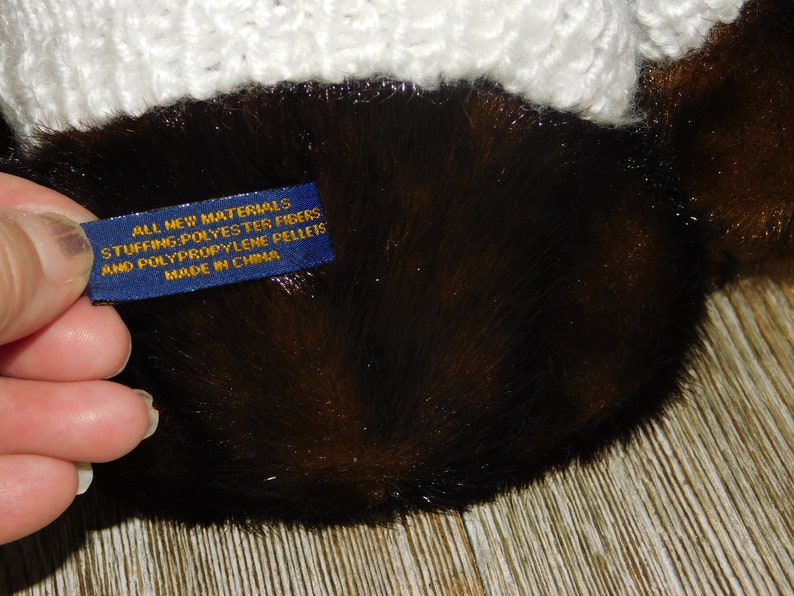 May include: Close-up of a blue label with gold text that reads "All New Materials Stuffing: Polyester Fibres and Polypropylene Pellets Made in China".